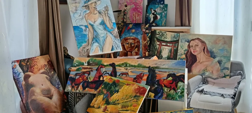 Atelier de Delia Teo : toiles réunies devant la fenêtre, femme en robe bleue au chapeau, troupeau de chevaux, figure égyptienne, portique japonais et portraits